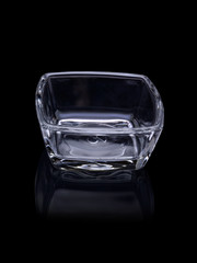 Square tray for food and roasting from transparent glass on a black background, with reflection