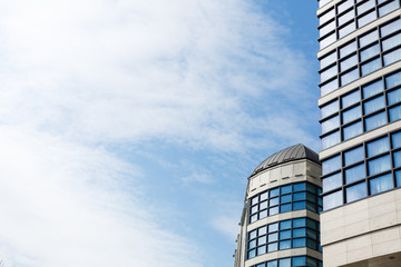 Obraz premium Skyscapers in big city, blue sky on background. Modern commercial buildings with glass facade. Cloudy sky reflecting in window glass. Construction, real estate, modern architecture