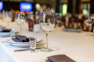 Wine glass and shot glass on a table in restaurant. Table setting for wedding reception, birthday party, banquet, celebration. White plates and black napkin