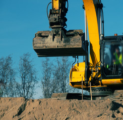 Excavator in the process of leveling the slope of the road