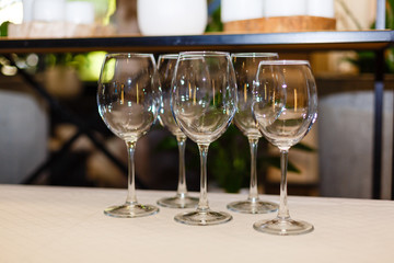 Wine glasses at bar counter. Group of five empty wine glasses. Preparation for a party or celebration