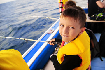 little boy fishing with a spinning boat from a boat.