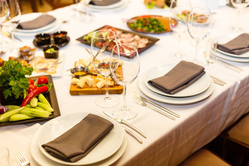 Restaurant table served with assortment of meals. Plate with vegetables, cheese platter, fish platter. Banquet, reception, celebration