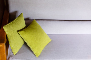 Part of grey sofa with green toss pillows. Living room interior design