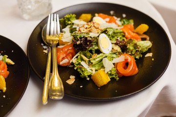 Salmon Salad with spinach, cherry tomatoes, corn salad, baby spinach, fresh mint and basil. Home made food. Concept for a tasty and healthy meal. Dark background. Top view. Close up