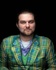 handsome serious concentrated bearded man in green plaid blazer looking at camera isolated on black