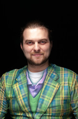 portrait of cheerful handsome stylish bearded man in green checkered blazer looking at camera isolated on black