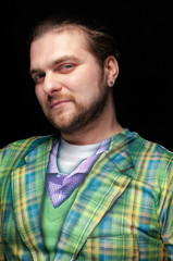Obraz premium portrait of handsome confident bearded man with stylish and earring in green elegance blazer looking at camera isolated on black