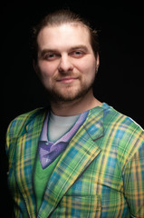 handsome cheerful positive bearded man with stylish hair in green checkered coat smile and looking at camera isolated on black