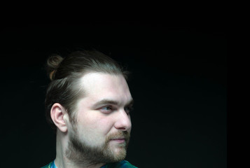 side view of head of handsome concentrated man with stylish beard and elegance hair bun looking away isolated on black