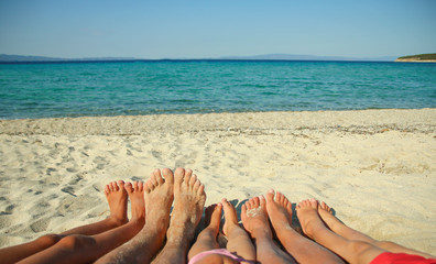 Family feet on the sand on the beach