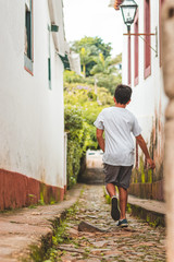 Menino caminhando por beco em cidade historica de Tiradentes de Minas Gerais