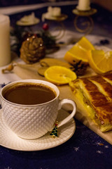 Festive Christmas table with candles with strudel, oranges and coffee