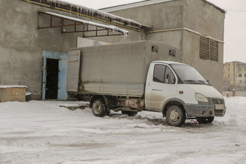 A truck stands in front of a warehouse ramp for unloading or loading.