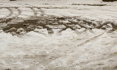 Snow puddle, with traces of car wheels