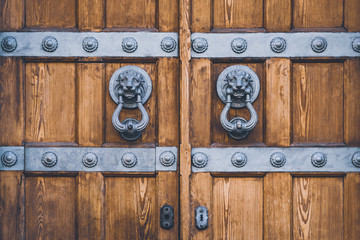 Detail of an antique wooden door with lion knockers made of cast iron