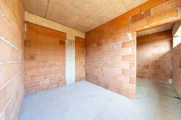 Unfinished room interior of building under construction. Brick red walls. New home.
