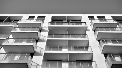Sun rays light effects on urban buildings. Fragment of modern residential apartment with flat buildings exterior. Detail of new luxury house and home complex. Black and white.