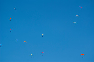 Colorful paratroopers flying over a blue sky. Image.