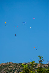 Colorful paratroopers flying over a blue sky. Image.