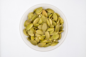 top view pumpkin seeds in white bowl isolated on white background