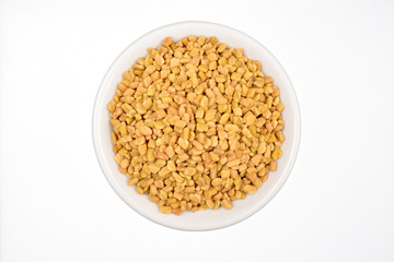 fenugreek seeds in bowl isolated on white background, top view 