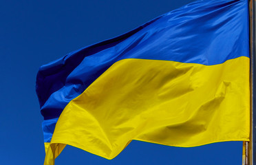 Blue and yellow Ukrainian national flags on a flagpoles against a blue sky