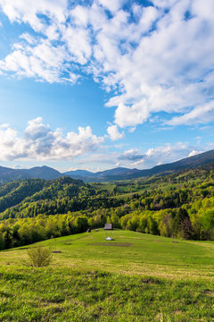 Carpathians countryside in springtime. wonderful sunny weather with dynamic cloud formations on the blue sky. forested rolling hill with rural fields in evening light. 