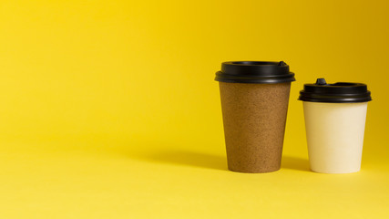 Coffee to go cups on yellow background. Copy space. Morning coffee concept.
