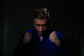 portrait of a handsome young man in a shirt fists fists on a black background