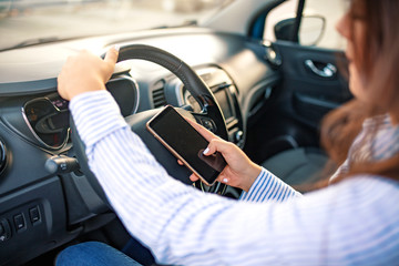 Close up of female hand holding smatrphone and typing while driving. Woman texting message using...