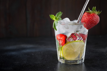 Detox lemonade or mojito with lime and strawberry in glass. Summer healthy freshness drink.