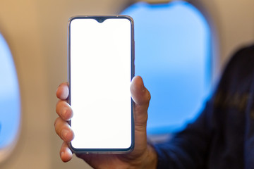 Mockup smartphone airplane. Young attractive european man holding blank screen smartphone in hands in airplane. Mock up for a game, mobile application, web site a horizontal oriental. Stock photo.