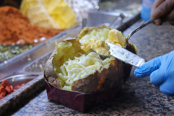 Die Vorbereitung von einem Kumpir mit K&auml;se und Butter 