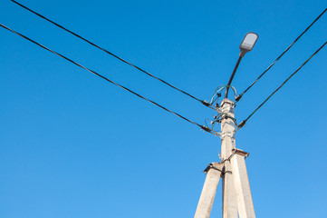 Electric pole and high voltage wires against the blue sky. Industrial landscape
