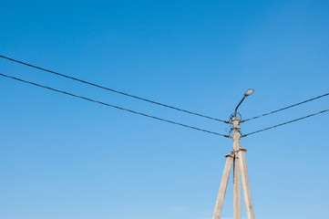 Electric pole and high voltage wires against the blue sky. Industrial landscape