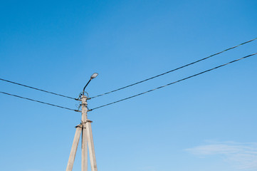 Electric pole and high voltage wires against the blue sky. Industrial landscape