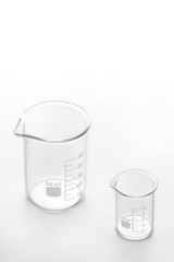 two empty transparent glass beakers 50 ml and 10 ml on a white background, showing comparison of size and volume