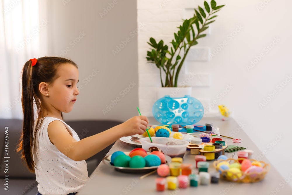 Wall mural little girl painting easter eggs in the kitchen