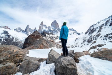 Een wandelaarvrouw met een blauwe jas aan de voet van de Fitz Roy-berg in Patagonië, Argentinië