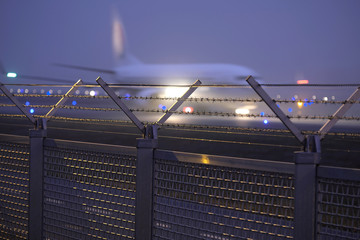 Sicherheitszaun und Flugzeug im Nebel auf Rollbahn am Flughafen Frankfurt - Stockfoto