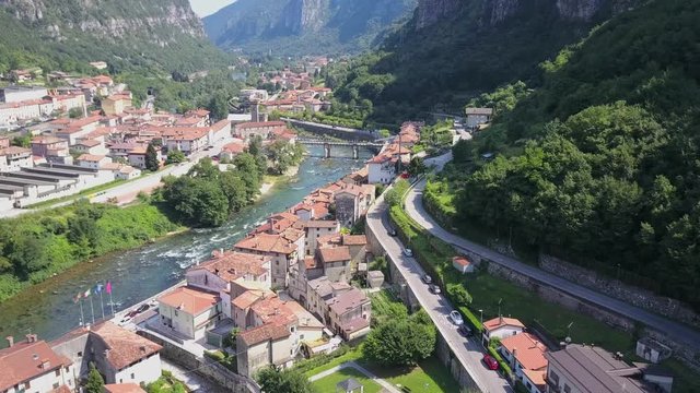 Aerial view tilting up shot, revealing the city, river and valley of Valstagna Italy.