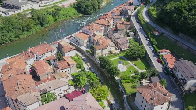 Aerial view moving down shot, scenic view of houses, road and river Brenta in valstagna Italy.