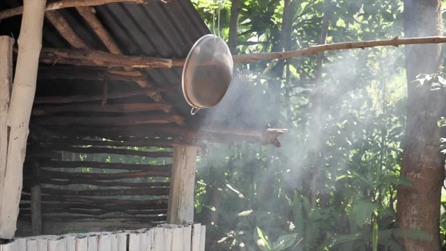 Full shot, mesh strainer hanging on a bamboo stick, smoke slowly rising up in the background.