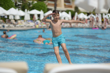 Naklejka premium Boy having fun making fantastic jump into swimming pool on summer vacations.