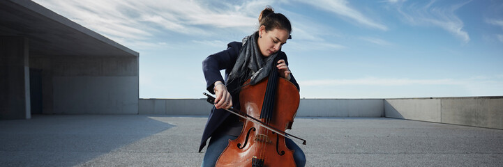 beautiful girl plays the cello with passion in a concrete environment