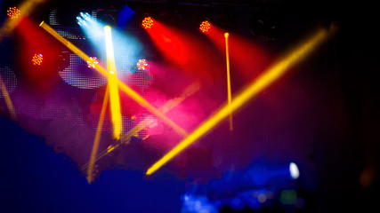 Stage lighting with bright spotlights during a night rock concert. Blurred background.