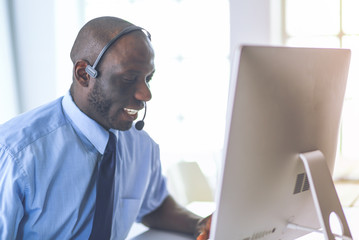 African american businessman on headset working on his laptop