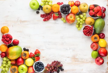 Plexiglas foto achterwand Rainbow fruits background, strawberries raspberries oranges plums apples kiwis grapes blueberries mango persimmon on white wooden table, top view, copy space for text, selective focus © Liliya Trott