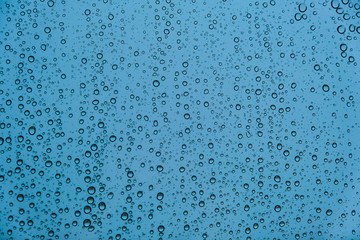 Raindrops on Transparent Glass Surface on a Cold Snowy Winter Background